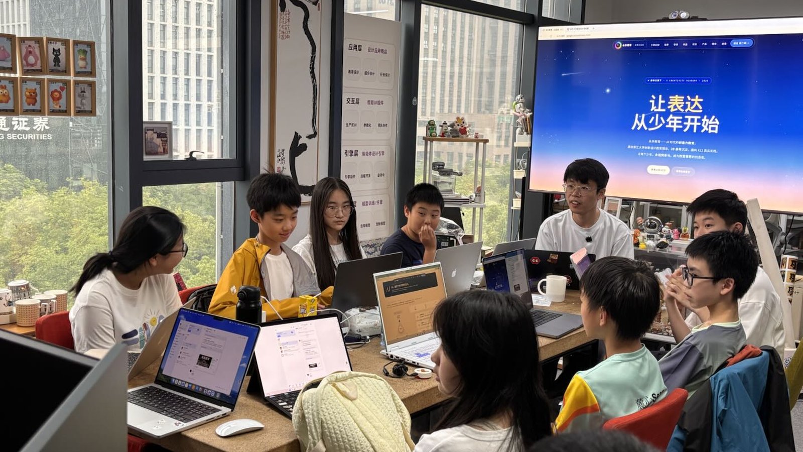 少年 CEO 第一期 · 第一次开课现场 · 9 位学员与邱懿武围桌讨论，背景大屏显示 yongle.school 官网