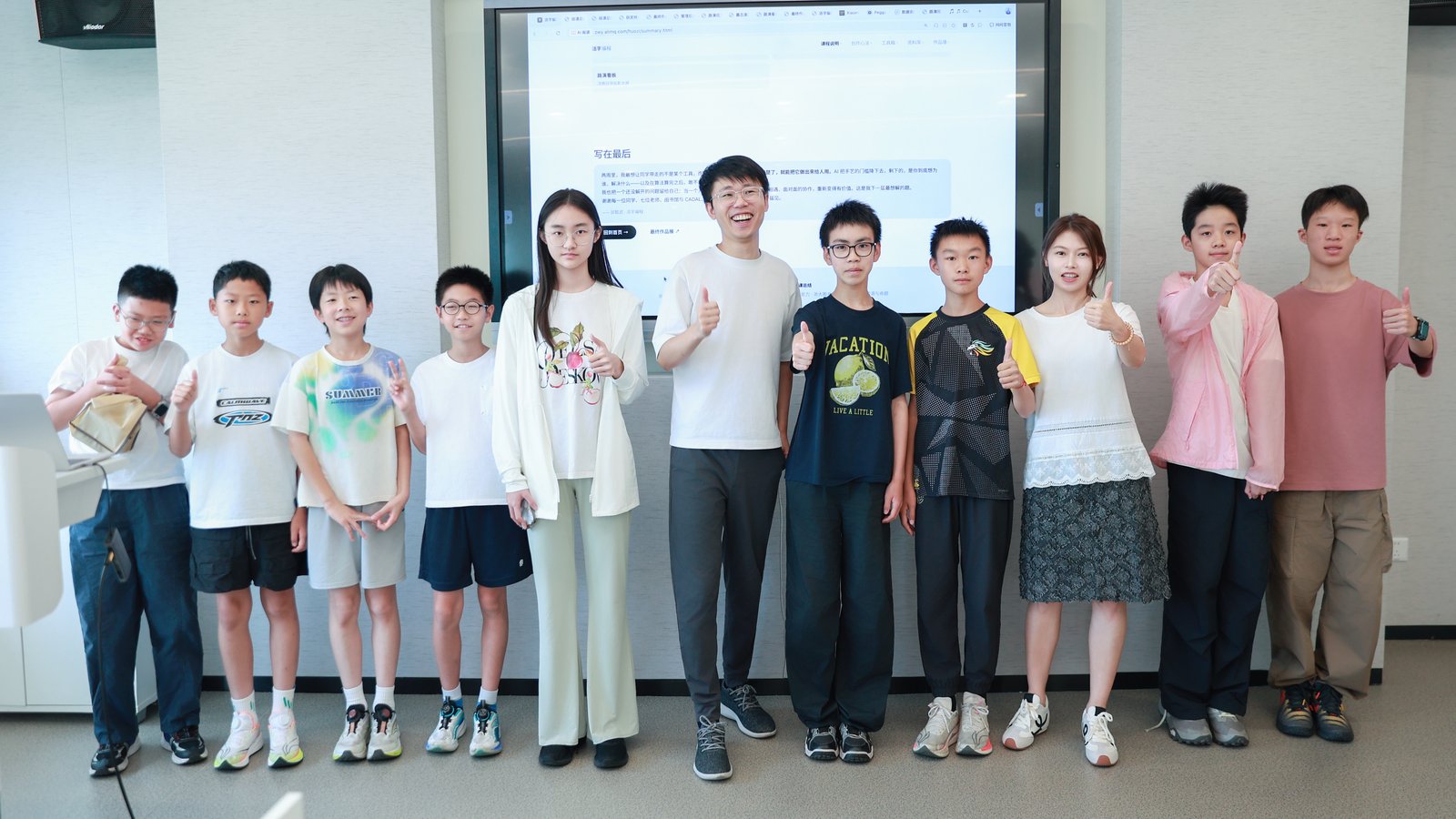 活字编程暑期夏令营 · 少年 CEO 学员与邱懿武及导师在浙大教室合影 · 背景大屏展示活字编程课程页
